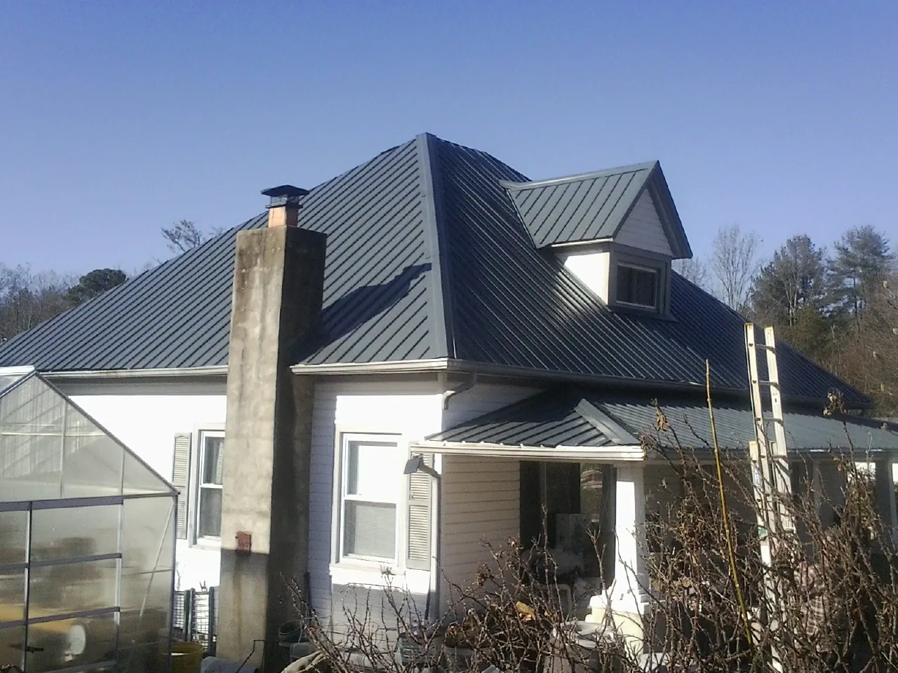 Dark blue standing seam metal roof on a white farmhouse with dormer — Slate & Tile Roof Repair by Roofing Brothers in Tobyhanna