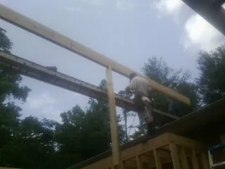 Carpenter setting a ridge beam over a new addition frame — Ice Dam Removal by Roofing Brothers in Tobyhanna