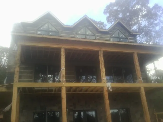 Dormers and porch framing on a large log home under construction — Roof Coating work by our crew in Tobyhanna