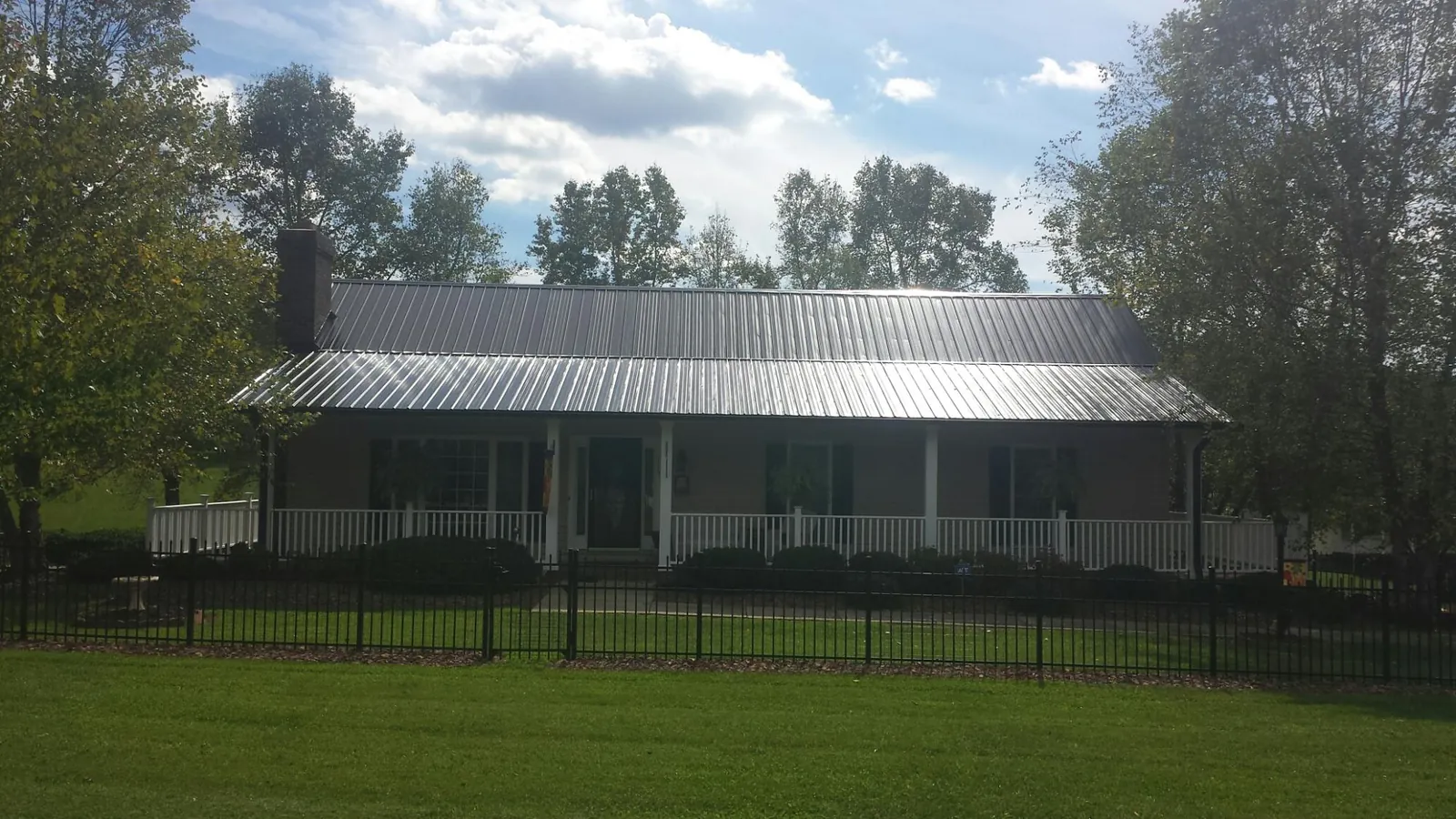 Gray metal roof on a brick ranch with a full width front porch — Gutter Guard Installation work by our crew in Tobyhanna