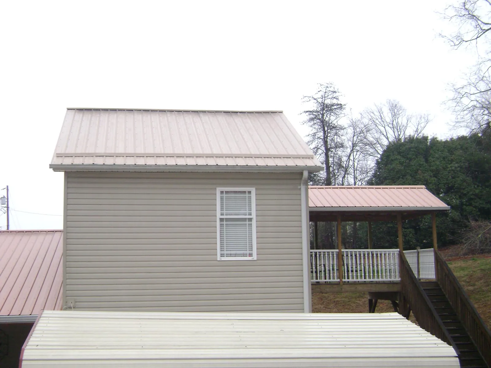 Tan metal roofs on a two story addition and attached porch, from a Roof Replacement job in Tobyhanna